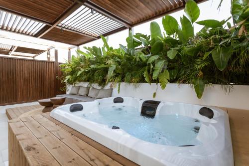 Una bañera grande en una habitación con plantas. en HUGme Suite, en Kalithies
