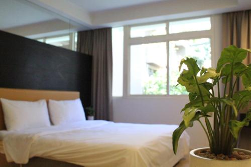 a bedroom with a bed with a plant next to a window at 喃行旅-一房一車位 毛孩友善客房數量有限請先預約 in Tainan