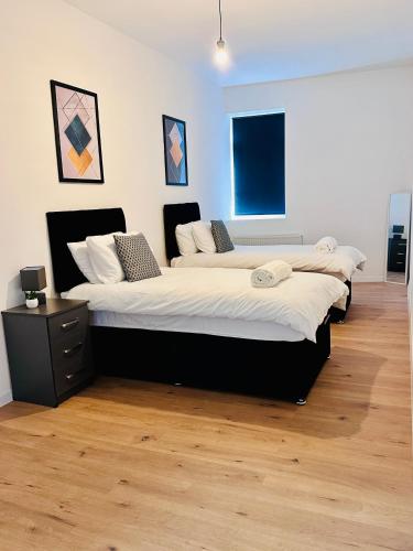 three beds in a room with wooden floors at Family & Contractor Haven Suites Mexborough in Mexborough