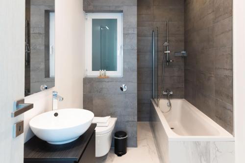 a bathroom with a sink and a tub and a toilet at Villa Ixoria Unit 2 with Rooftop Pool by ArcoBnb in St Julian's