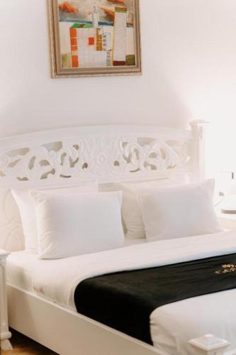 a white bed with white pillows and a picture on the wall at Golden Hotel in Pristina