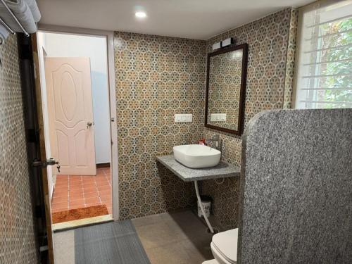 にあるPhalguni Farm Stayの洗面台とトイレとピンクのドアのあるバスルーム