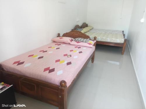 a bedroom with two twin beds with pink sheets at Grace Residency in Tiruchchendūr