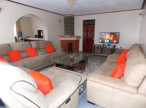 a living room with two couches and a tv at The Nook at Axis Garden Suites, Solo Ensuite Near JKIA,SGR,Nairobi express way with Workspace in Syokimau