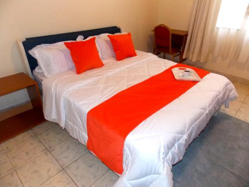 a bedroom with a large bed with red and white pillows at The Nook at Axis Garden Suites, Solo Ensuite Near JKIA,SGR,Nairobi express way with Workspace in Syokimau