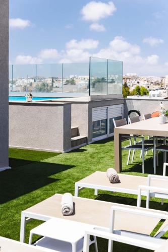 a patio with white tables and chairs and a pool at Villa Ixoria Unit 2 w Rooftop Pool by Arco Collection in St. Julianʼs
