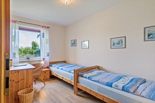 a bedroom with two beds and a desk and a window at Ferienhof Kiesow in Nordstrand