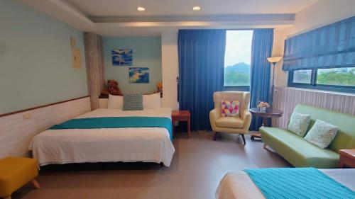 a hotel room with two beds and a chair at Bestime B&B in Jiji