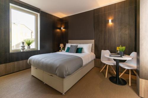 una camera da letto con un letto, un tavolo e una finestra di Hounslow Central Studio Aparments a Hounslow