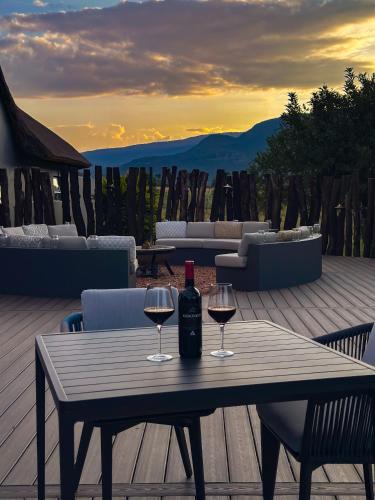 a wooden table with two glasses of wine on a deck at Honeyguide Conservation Lodge in Golders Green