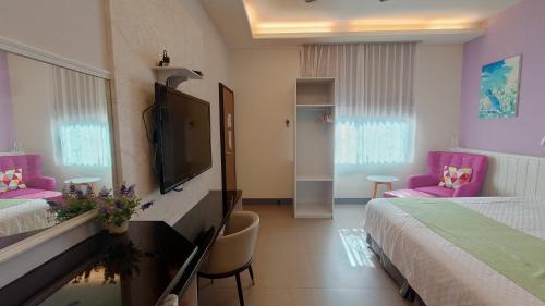 a hotel room with two beds and a flat screen tv at Bestime B&B in Jiji