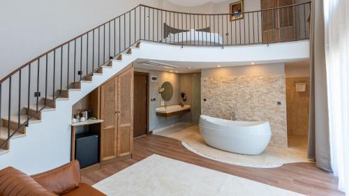 a bathroom with a tub under a staircase at Cunda Kızılca Deluxe Hotel & SPA in Ayvalık