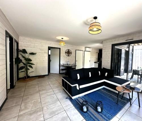a living room with a black couch and a blue rug at Meublé de Tourisme 4 étoiles avec Jacuzzi & Sauna in Mios