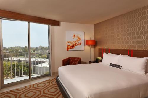 a hotel room with a bed and a large window at Hotel Angeleno in Los Angeles