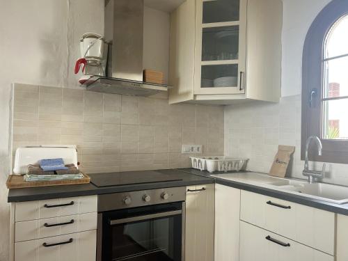a kitchen with white cabinets and a stove top oven at BERGANTIN 109 by SOM Menorca in Fornells