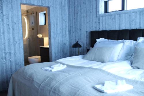 a bedroom with a white bed with two towels on it at Bakkabyggd - A lake view villa in Ólafsfjörður