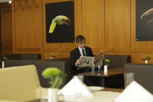 a man in a suit sitting at a table with a laptop at SOALTEE Hotel by Trip Inn Frankfurt Messe Tagungshotel in Frankfurt/Main