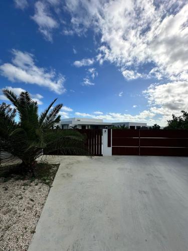 a white house with a fence and a palm tree at Havre de paix luxueux avec vue mer imprenable in Dumbéa