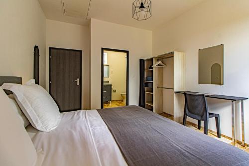 une chambre avec un grand lit et un bureau dans l'établissement Le Chai Villa, à Thénac