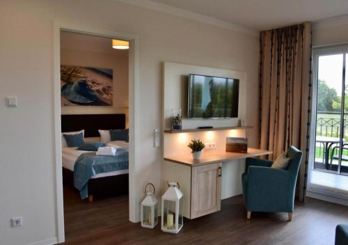 a hotel room with a bed and a desk and a tv at Aparthotel Waterkant Suites - Fewos am Meer mit SPA in Börgerende-Rethwisch