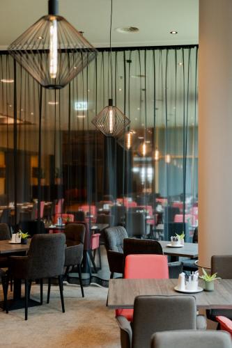 a dining room with tables and chairs and lights at Steigenberger Airport Hotel Amsterdam in Schiphol