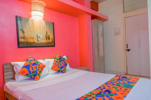 a bedroom with a pink wall and a bed with colorful pillows at FabHotel Saraswati Niwas in Pune