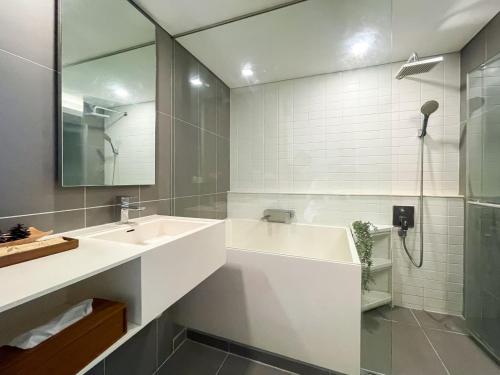 a white bathroom with a sink and a shower at Elegant 1BR Condo - Ultra Fast WiFi - BTS On-Nut in Bangkok
