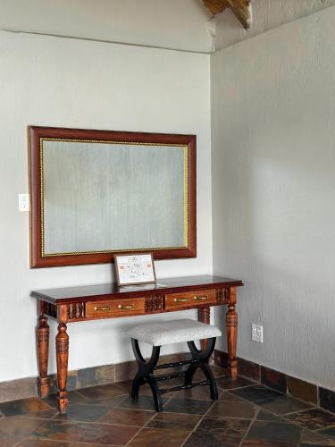 a desk with a chair and a mirror on a wall at Honeyguide Conservation Lodge in Golders Green