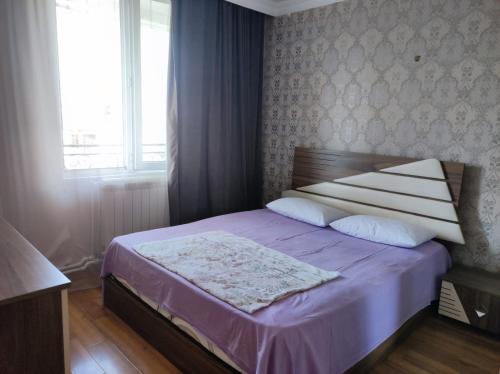 a bedroom with a bed with purple sheets and a window at Guesthouse Davit Guramishvili 21 in K'obulet'i