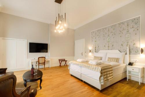 a bedroom with a white bed and a living room at GOYA Vitality Hotel in Voderady