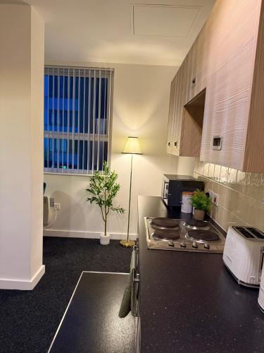 a kitchen with a stove and a counter top at Luxury and Cosy Apartment near Old Trafford M16 ,Free Private Parking,Fast Wi-Fi,Self Check-In Anytime Perfect For Late Arrivals, 5 Minutes to Old Trafford Stadium in Manchester