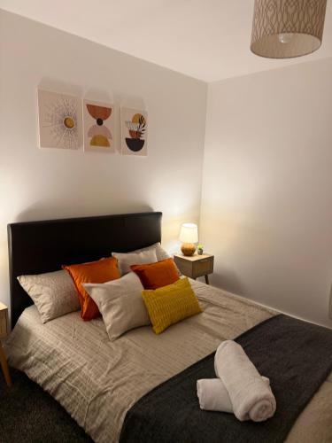 a bedroom with a large bed with colorful pillows at Luxury and Cosy Apartment near Old Trafford M16 ,Free Private Parking,Fast Wi-Fi,Self Check-In Anytime Perfect For Late Arrivals, 5 Minutes to Old Trafford Stadium in Manchester