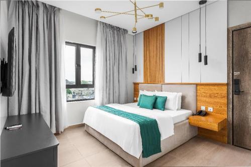 a bedroom with a large white bed with blue pillows at Vertus Hotel and Suites in Benin City