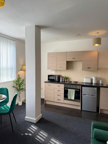 a kitchen with wooden cabinets and a table and chairs at Luxury and Cosy Apartment near Old Trafford M16 ,Free Private Parking,Fast Wi-Fi,Self Check-In Anytime Perfect For Late Arrivals, 5 Minutes to Old Trafford Stadium in Manchester