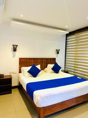 a bedroom with a large bed with blue pillows at J7 Villaj Resort in Trincomalee