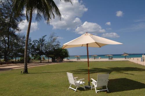two chairs and an umbrella on the beach at Pigeon Island Beach Resort and Spa in Nilaveli