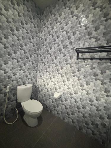 a bathroom with a toilet and a wall covered in paper at Idaman Home in Kuta Lombok