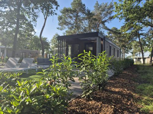 a black house in a garden with chairs and trees at Casa Sallandia met Outdoor Wellness! in Haarle