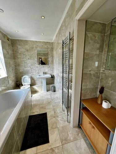 a bathroom with a tub and a sink at Spacious Ensuite Room With Garden View in Dagenham