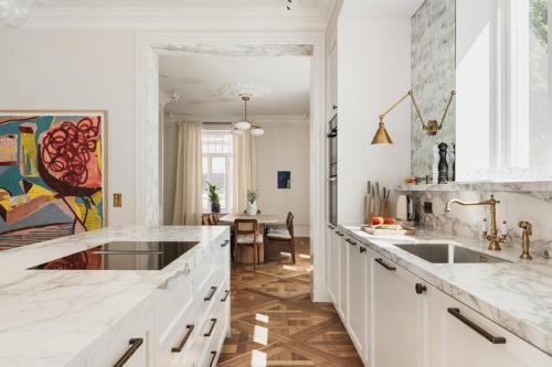 a white kitchen with a sink and a table at CygnusPool °BBQ °Sauna °Parking °King °Netflix°Gym in Oslo