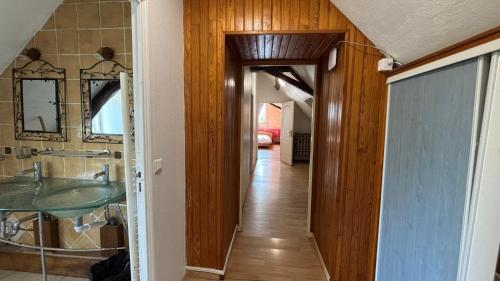 a hallway leading to a bathroom with a sink and a mirror at Maison familiale à la campagne in Vallères