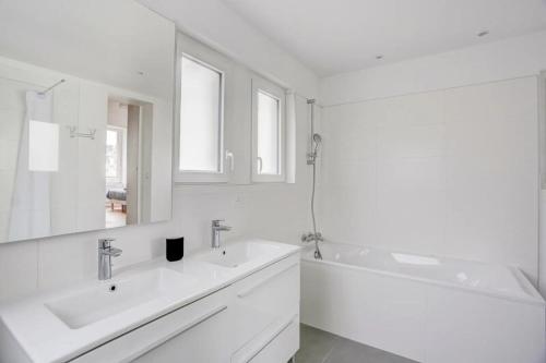 Un baño blanco con dos lavabos y una bañera. en L Abri Côtier, en Saint-Cast-le-Guildo