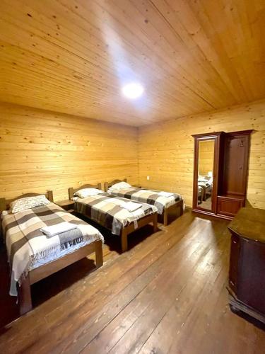 a room with three beds in a wooden room at Готель Пацьорка in Kremintsi