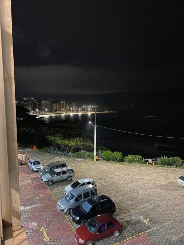 a group of cars parked in a parking lot at night at Mirante do Ipiranga Apartment in Guarapari