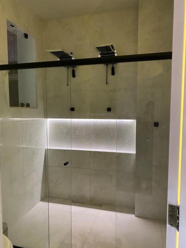 a walk in shower with a glass wall at Mirante do Ipiranga Apartment in Guarapari