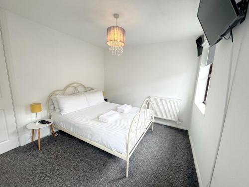 a small white bedroom with a bed and a chandelier at 2 bed house, walking distance Shrewsbury centre in Shrewsbury