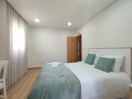 a bedroom with a large white bed with green pillows at Barcelos Habadia House in Lijó