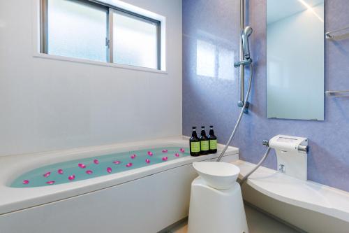 a bathroom with a tub and a toilet and bottles of wine at 最大16名 BBQ可能 駐車場3台 シアタールーム付きのグループ旅行におすすめ宿 The MELIA in Yomitan