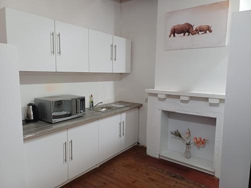 a kitchen with white cabinets and a microwave and a fireplace at 19 on Smit in Piet Retief