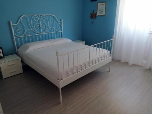 a bedroom with a white bed with a blue wall at Casa Vacanze Brezza Marina with beautiful garden in Quartu SantʼElena